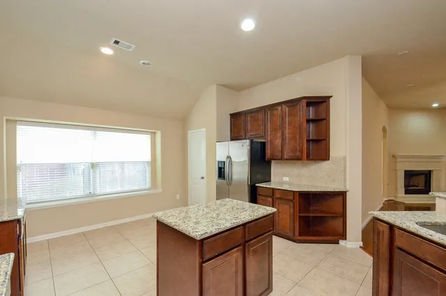 a kitchen with kitchen island granite countertop wooden cabinets a sink and a stove