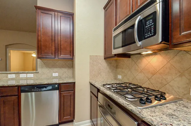 a kitchen with granite countertop stainless steel appliances stove top oven and cabinets