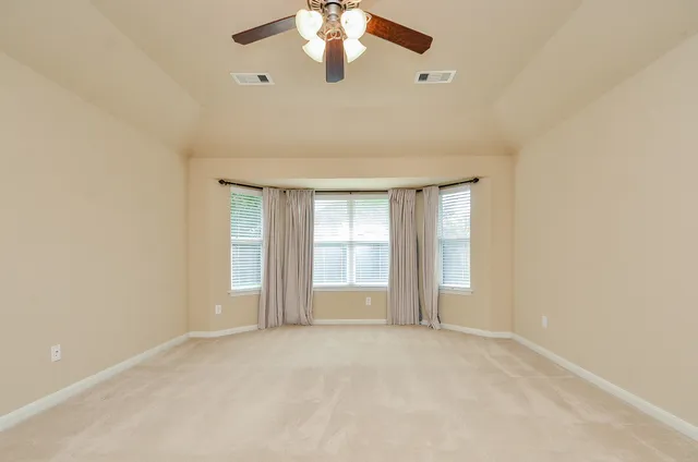 an empty room with chandelier fan and windows