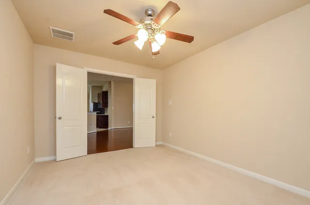 an empty room with closet and a ceiling fan