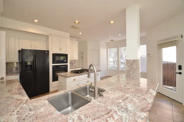 a kitchen with stainless steel appliances kitchen island granite countertop a refrigerator and a stove