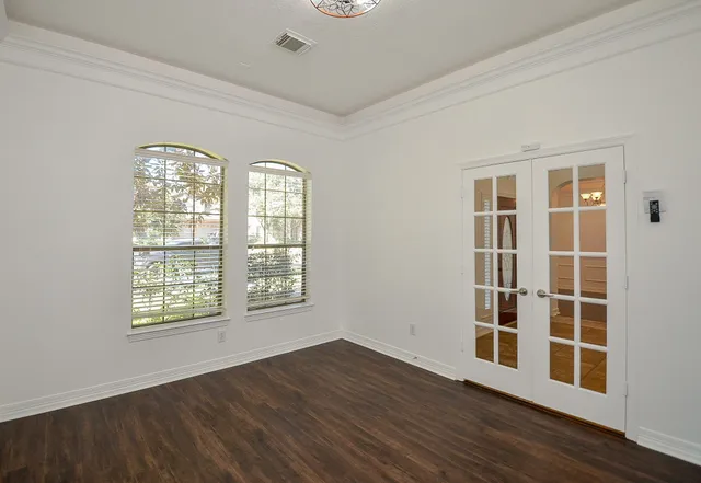 an empty room with wooden floor and windows