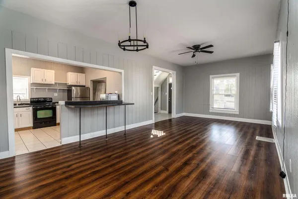 a view of a kitchen with a dishwasher a kitchen island wooden floor and a window