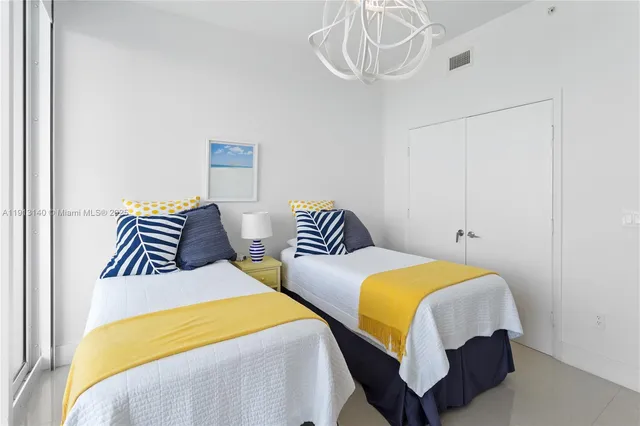 a bedroom with two beds and a chandelier