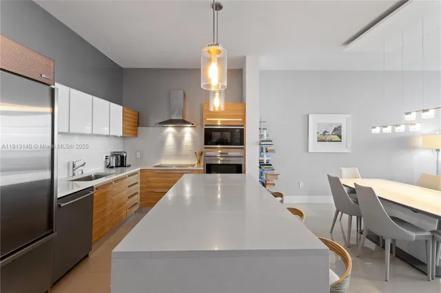 a large kitchen with stainless steel appliances granite countertop a stove refrigerator a dining table and chairs with the cabinets