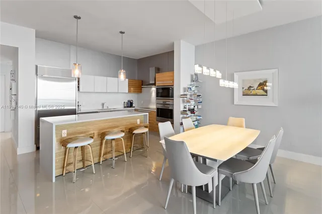 a kitchen with stainless steel appliances granite countertop a dining table chairs and a refrigerator