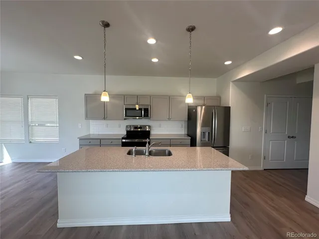 a large kitchen with stainless steel appliances a large counter top a stove a sink and a refrigerator