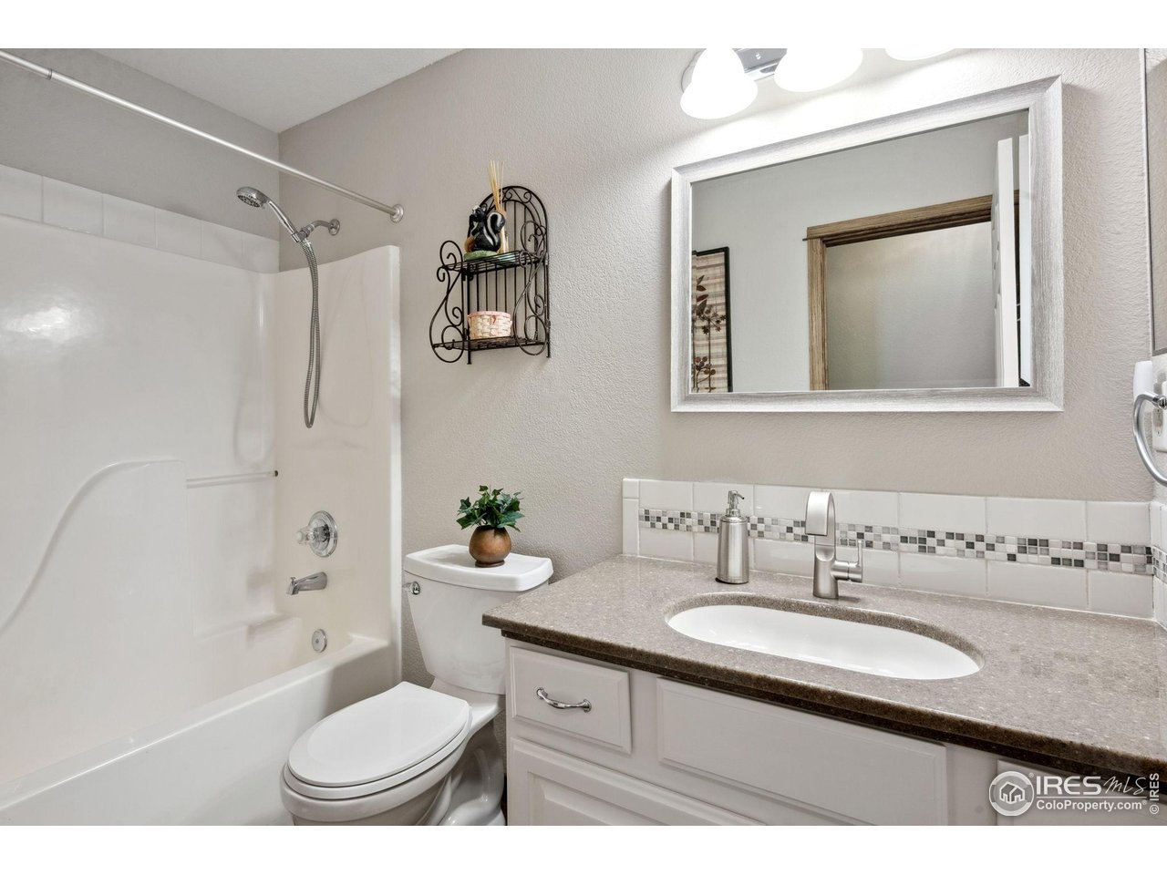 2131 68th Avenue Greeley, CO 80634 - Photo 16 of 39 a bathroom with a granite countertop sink toilet a mirror and bathtub