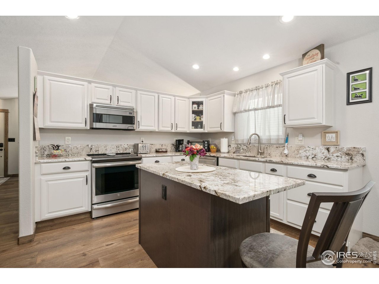 2131 68th Avenue Greeley, CO 80634 - Photo 5 of 39 a kitchen with kitchen island granite countertop a sink stove and white cabinets