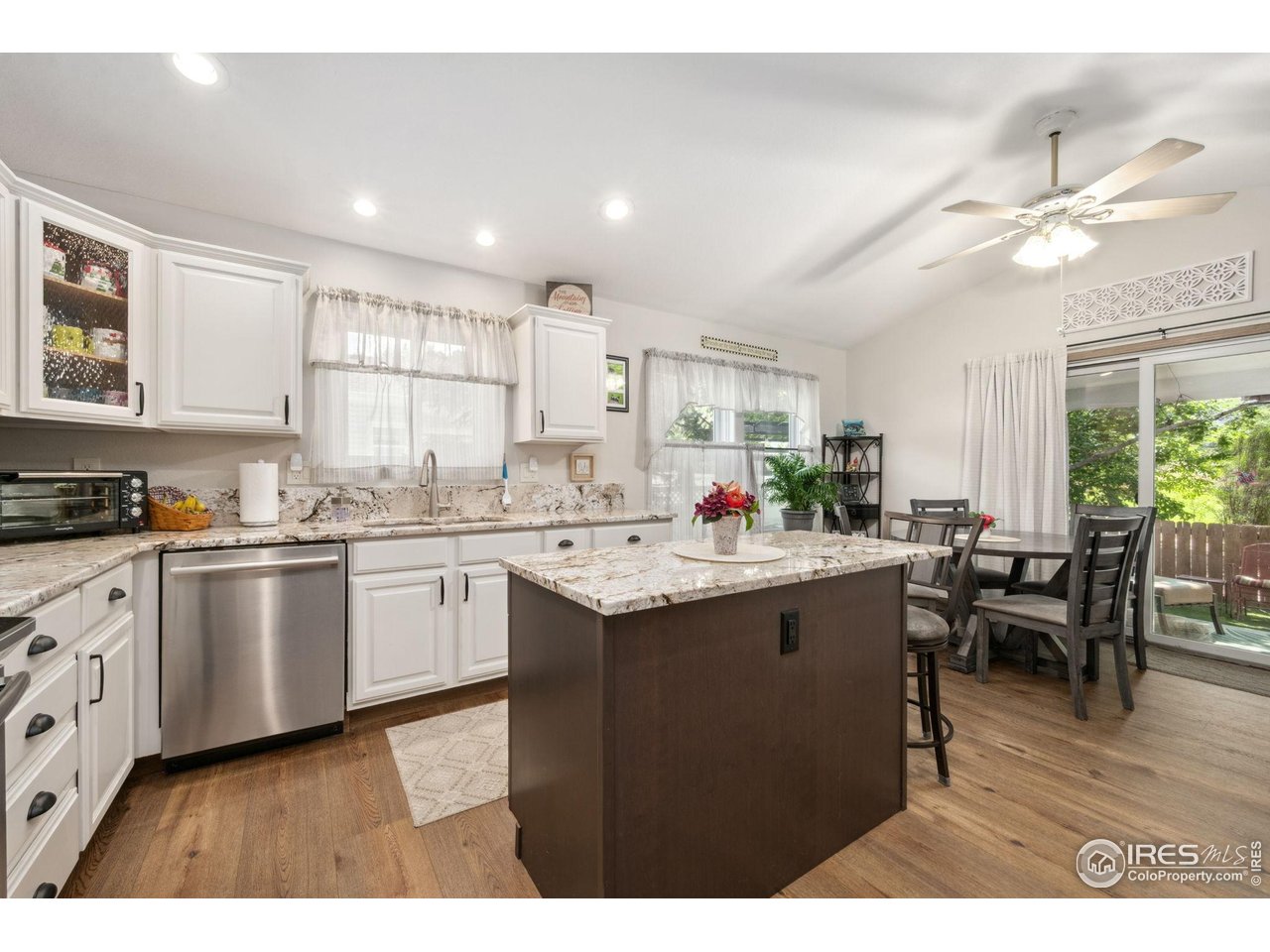 2131 68th Avenue Greeley, CO 80634 - Photo 7 of 39 a kitchen with stainless steel appliances granite countertop a sink dishwasher a stove a dining table and chairs with wooden floor