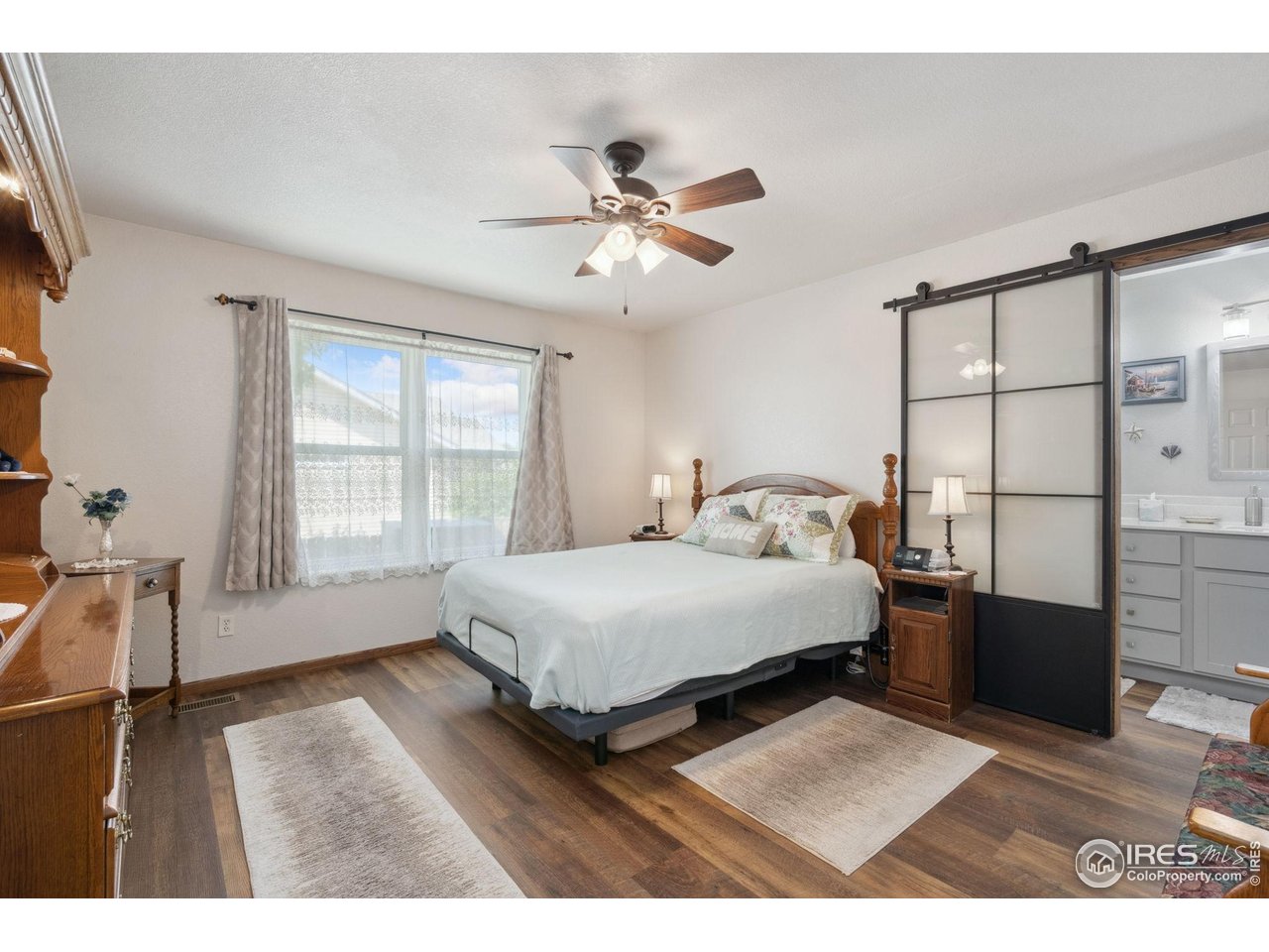 2131 68th Avenue Greeley, CO 80634 - Photo 10 of 39 a bedroom with a bed next to a window with a flat tv screen and dresser