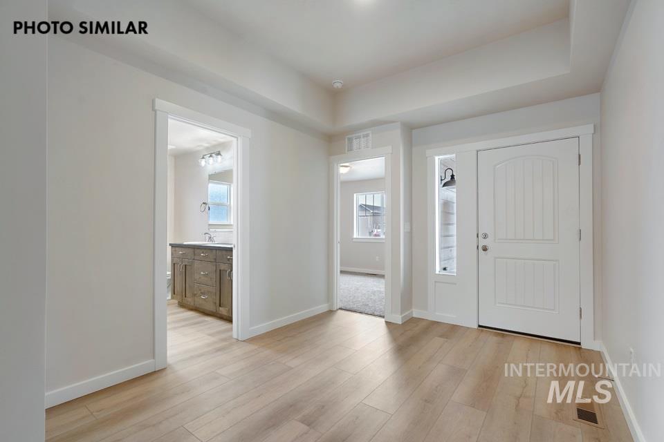 1645 Haystack Emmett, ID 83617 - Photo 2 of 33 Entryway featuring light wood-finish flooring, a paneled white entry door with an arched top, a sidelight with a black sconce, and recessed lighting