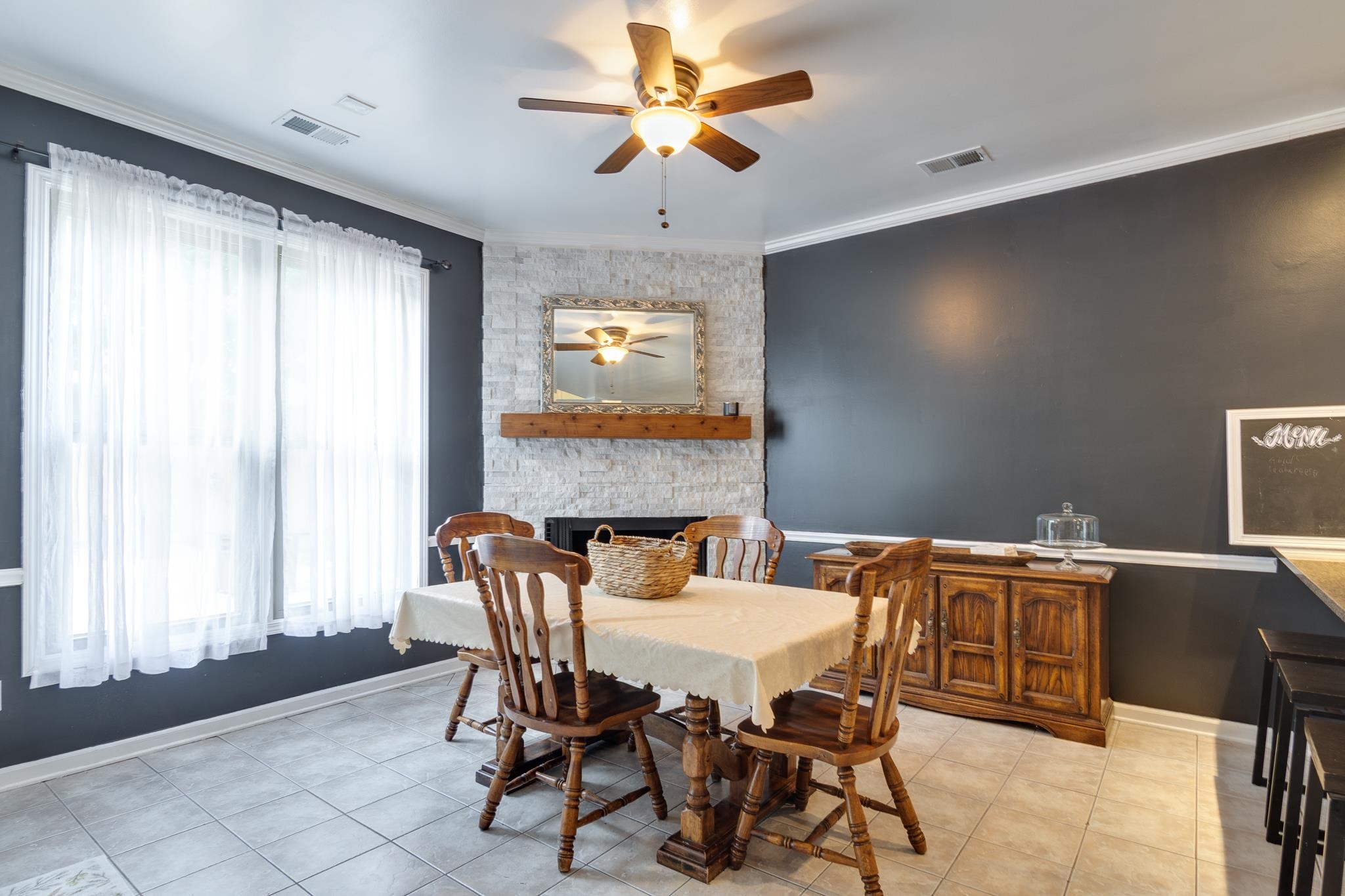 779 Early Earner Cove Collierville, TN 38017 - Photo 8 of 29 Breakfast area featuring a stone accent wall with a wood mantel, a ceiling fan with integrated lighting, and tile flooring