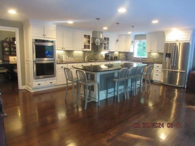 60 Raymond Road Sudbury, MA 01776 - Photo 9 of 21 a kitchen with stainless steel appliances granite countertop a stove a refrigerator a kitchen island a stove a dining table and chairs with wooden floor