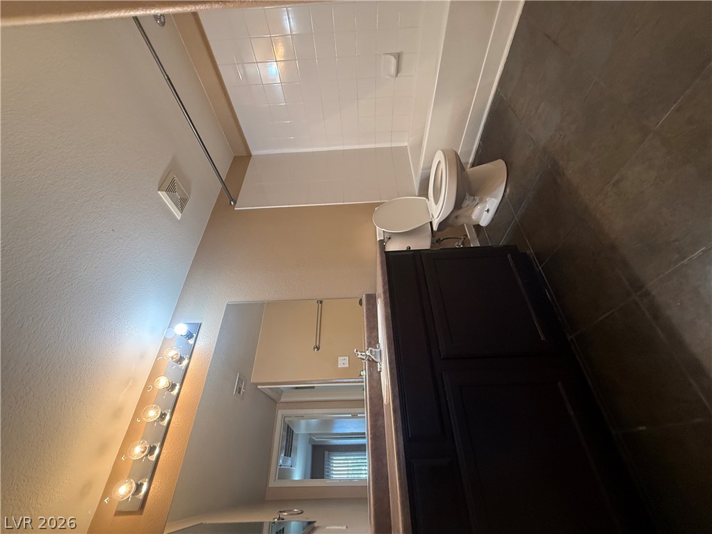 7255 West Sunset Road, Unit 2052 Las Vegas, NV 89113 - Photo 11 of 16 A well-appointed bathroom with dark wood cabinetry and a classic tub-shower combination.