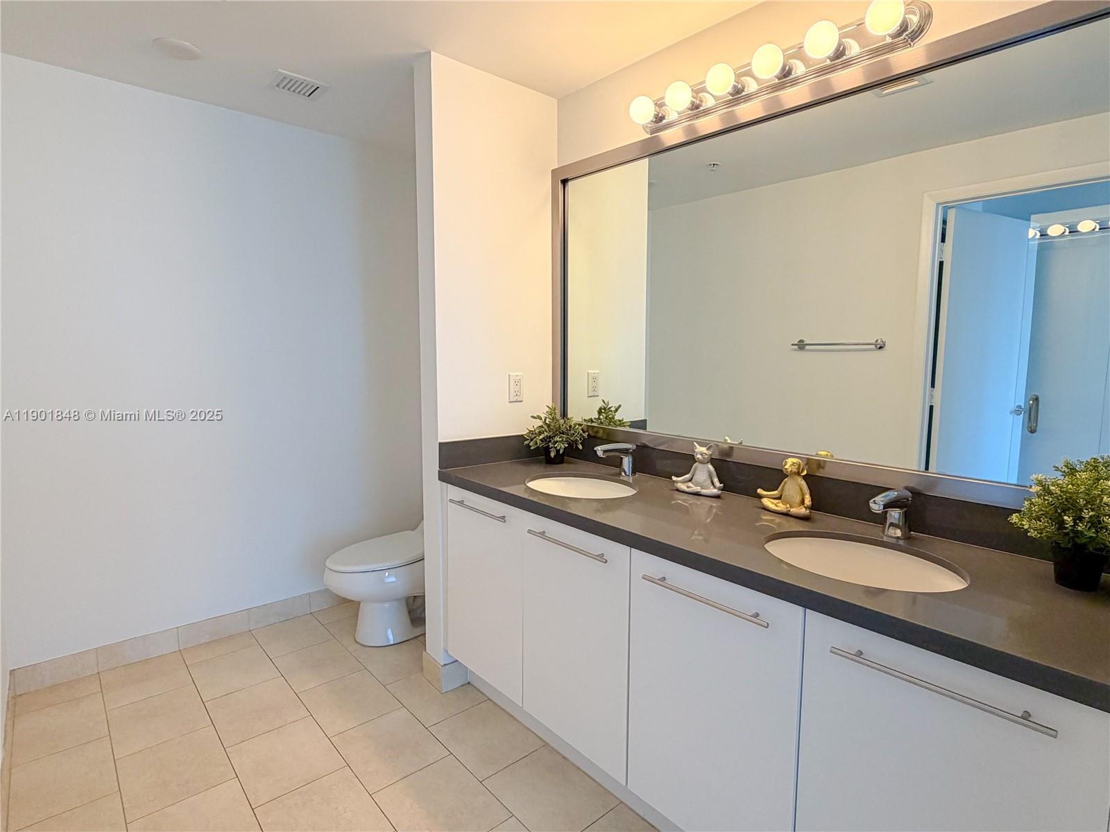 90 Southwest 3rd Street, Unit 2401 Miami, FL 33130 - Photo 33 of 68 a bathroom with a granite countertop sink a toilet and a mirror