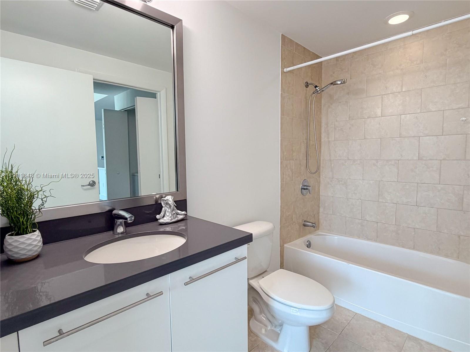 90 Southwest 3rd Street, Unit 2401 Miami, FL 33130 - Photo 41 of 68 a bathroom with a granite countertop sink toilet a shower and a mirror