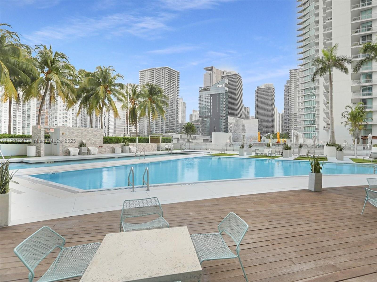 90 Southwest 3rd Street, Unit 2401 Miami, FL 33130 - Photo 53 of 68 a view of a swimming pool with a lawn chairs and palm trees