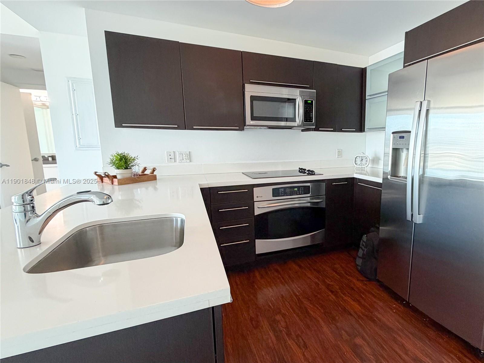 90 Southwest 3rd Street, Unit 2401 Miami, FL 33130 - Photo 8 of 68 a kitchen with stainless steel appliances a sink a stove a microwave and wooden floors