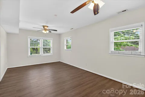 a view of an empty room with wooden floor and window