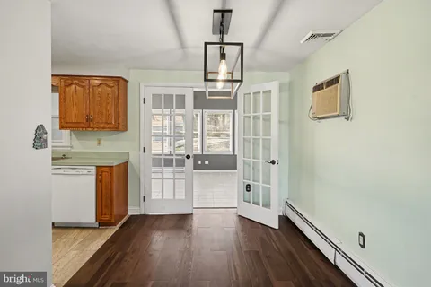 a view of a hallway with wooden floor and a kitchen