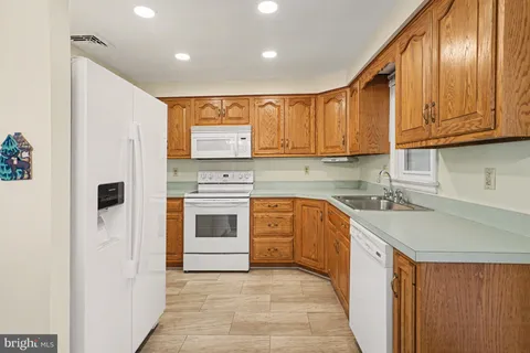 a kitchen with stainless steel appliances granite countertop a sink a stove a refrigerator with grey cabinets