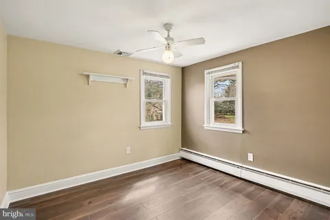 an empty room with wooden floor chandelier and windows