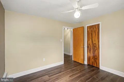 an empty room with wooden floor and fan