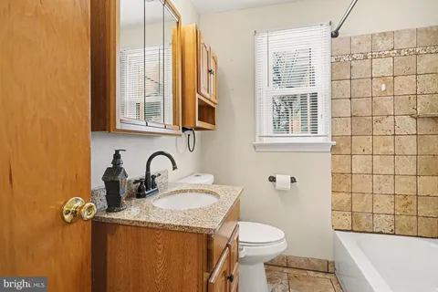 a bathroom with a granite countertop sink and a toilet