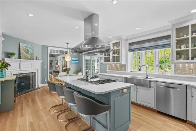 a kitchen with stainless steel appliances granite countertop a stove a sink dishwasher a dining table and chairs with wooden floor