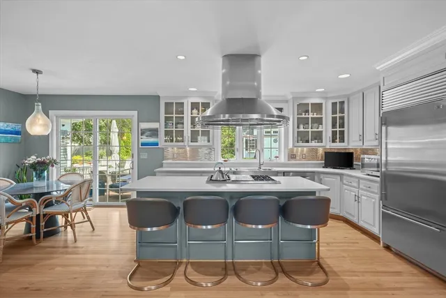 a kitchen with kitchen island granite countertop a stove and a dining table with wooden floor