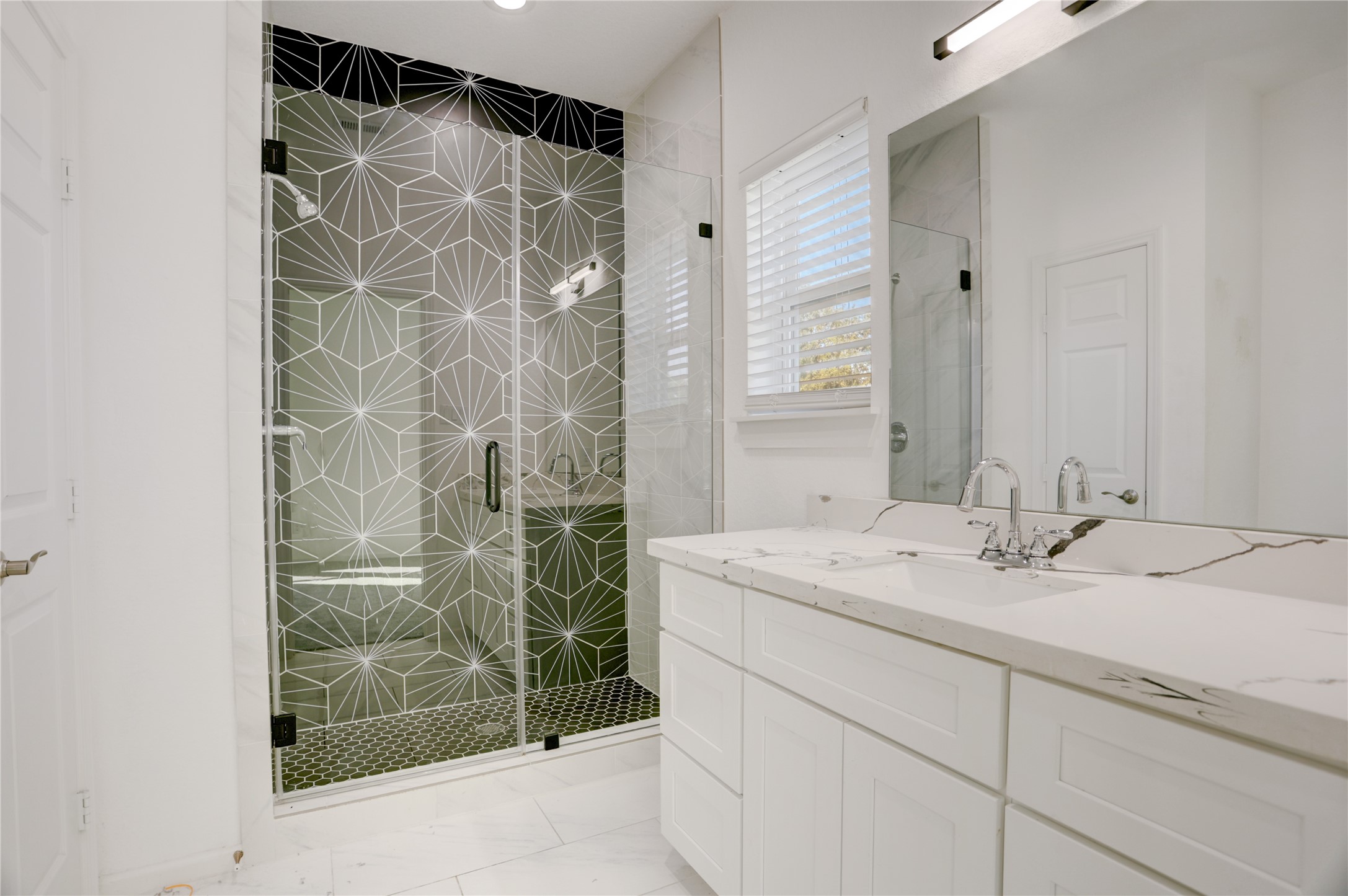 5317 Chennault Road, Unit A / B Houston, TX 77033 - Photo 18 of 27 This stunning primary bathroom blends modern luxury with thoughtful design. A spacious vanity with sleek quartz countertops offers ample storage and style, while the oversized walk-in shower becomes a true showpiece with its geometric glass design and contrasting tile floor.