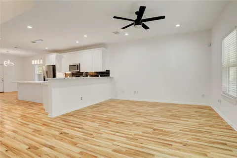 a large white kitchen with a refrigerator a stove top oven a sink dishwasher and wooden floor