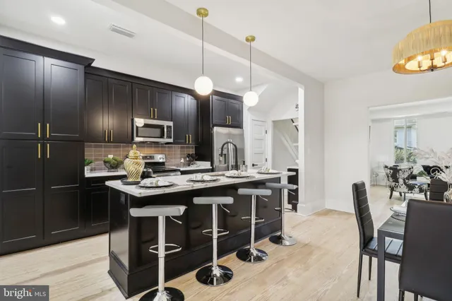 a kitchen with kitchen island a dining table chairs stainless steel appliances and wooden floor