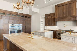 1141 East Lost Ridge Drive Washington, UT 84780 - Photo 36 of 108 Spacious kitchen featuring an expansive island with a light-toned countertop, floor-to-ceiling wood cabinetry, dual built-in ovens, and a custom wood range hood