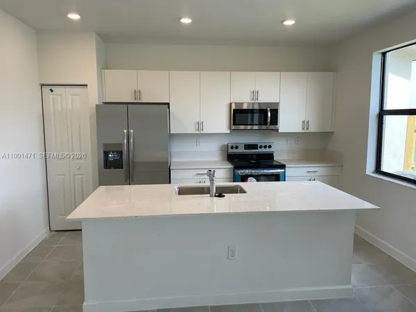 a kitchen with kitchen island a sink stainless steel appliances and window