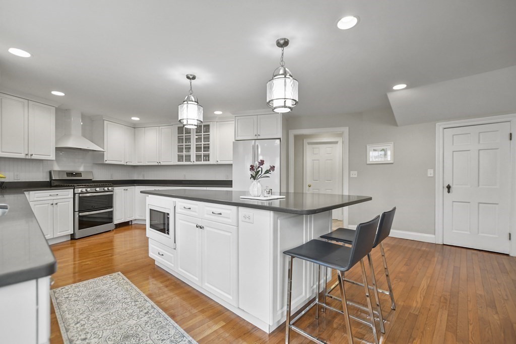 348 Webster Street Needham, MA 02494 - Photo 11 of 42 a large kitchen with stainless steel appliances kitchen island granite countertop a table chairs in it and wooden floors