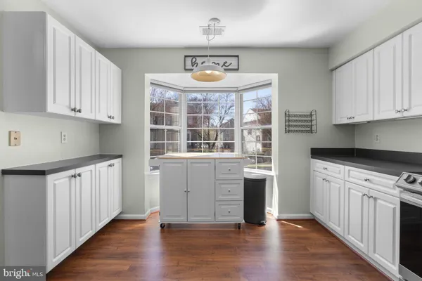 a kitchen with granite countertop a stove top oven a sink and dishwasher with white cabinets