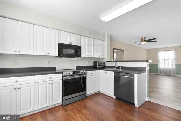 a kitchen with stainless steel appliances granite countertop a stove a sink dishwasher and a microwave oven with wooden floor