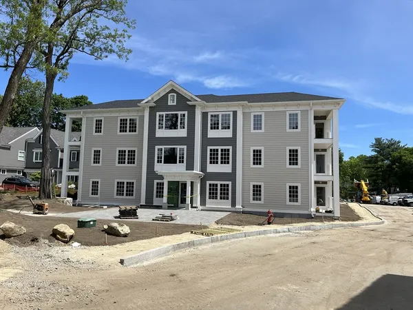 a front view of a building with lot of cars and trees