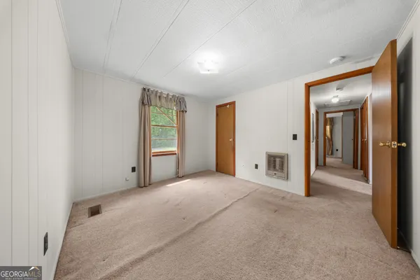 a view of an empty room with closet and a window