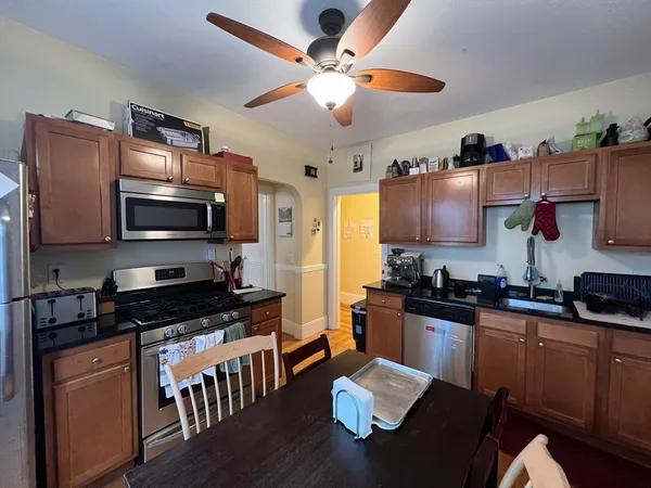 a kitchen with granite countertop stainless steel appliances a stove top oven a sink a dining table and chairs