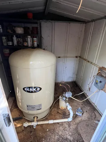 a room with water heater and wooden cabinets