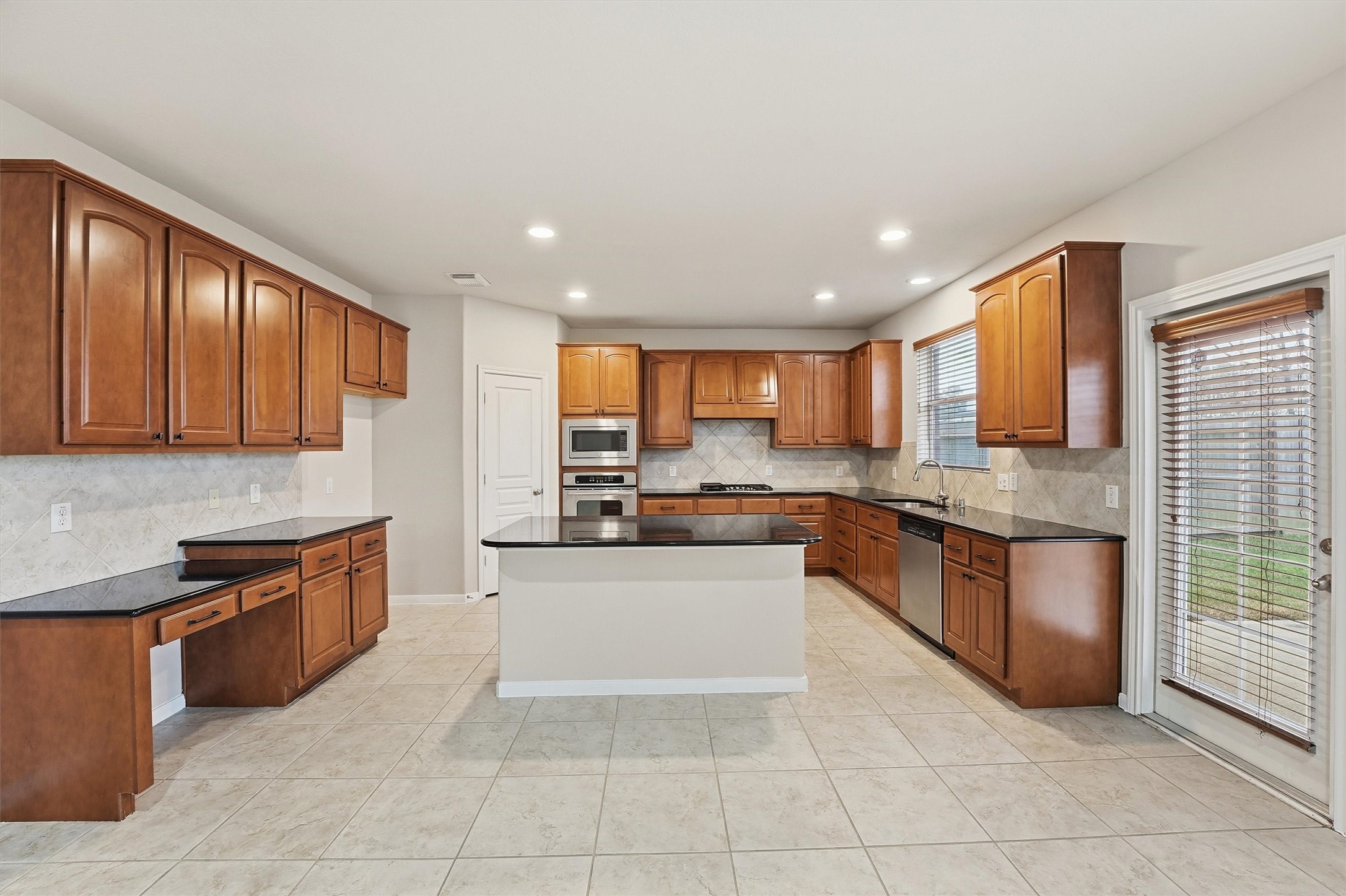 17415 Memorial Mills Drive Spring, TX 77379 - Photo 5 of 39 The kitchen showcases upgraded 42" maple cabinetry, granite countertops, and a large center island, complemented by 18" x 18" tile flooring, recessed lighting, and stainless steel appliances.