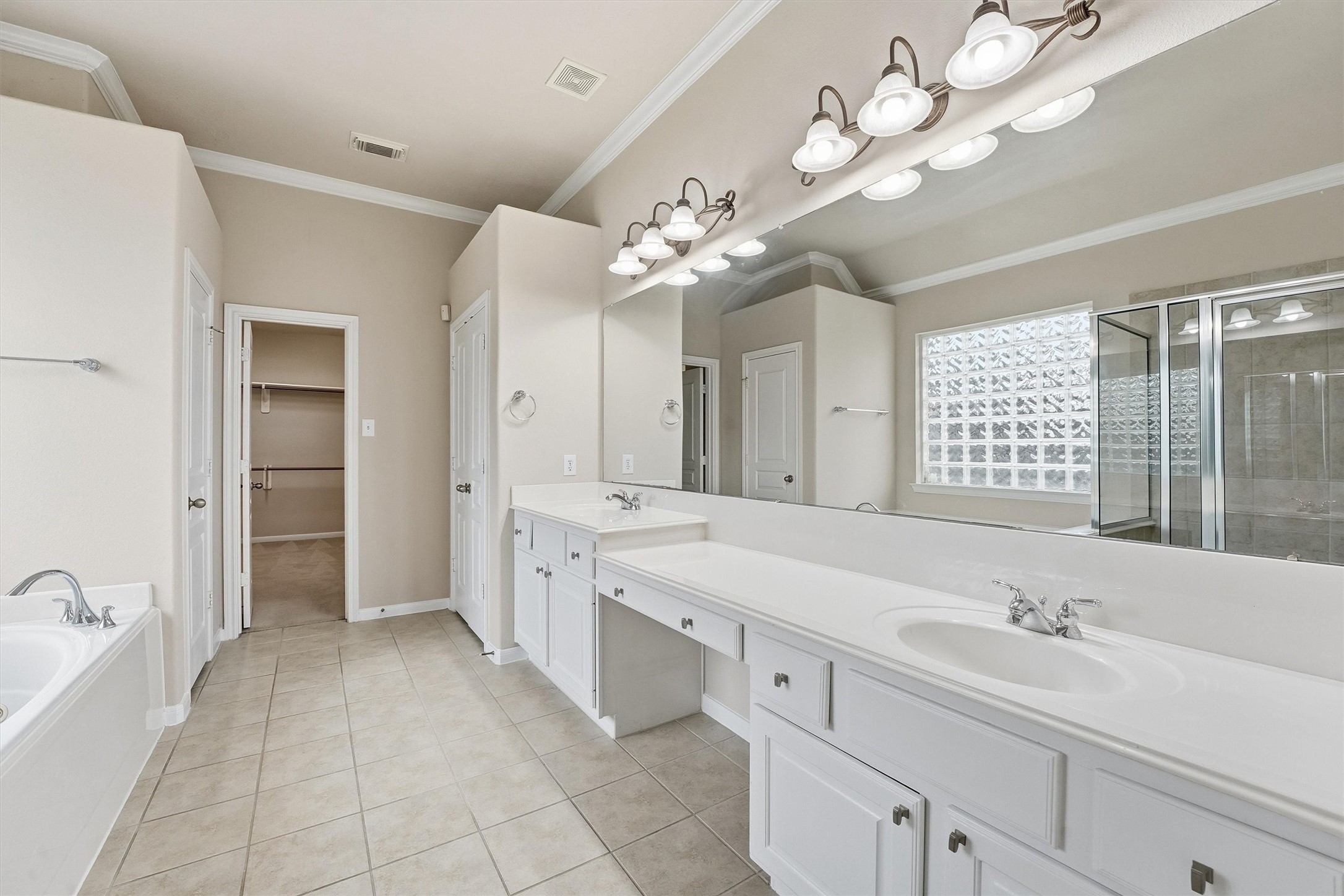 17415 Memorial Mills Drive Spring, TX 77379 - Photo 7 of 39 The primary bath offers dual sinks with a large vanity area, tile flooring, a jetted, soaking tub, and a spacious walk-in closet beyond. Separate walk-in shower (visible in mirror).