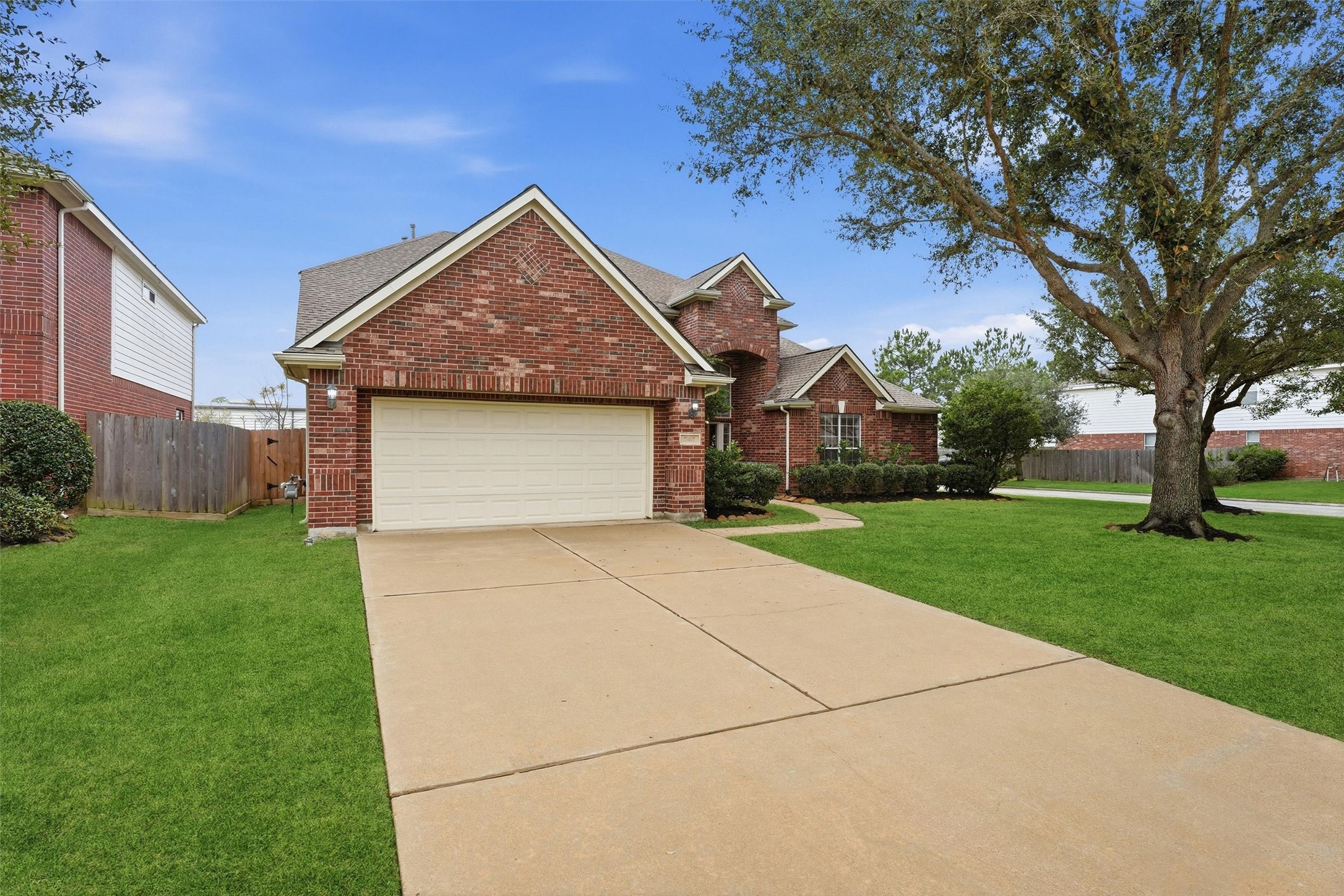17415 Memorial Mills Drive Spring, TX 77379 - Photo 9 of 39 Brick front elevation with mature landscaping, a two-car garage, and a curved walkway leading to the covered entry.