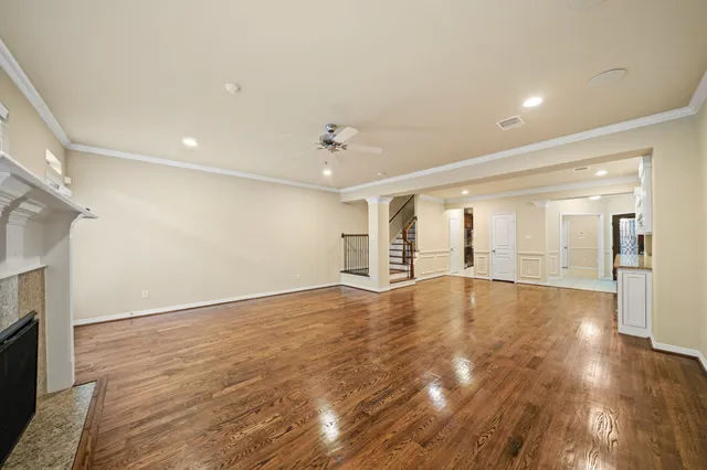 a view of an empty room with wooden floor and a fireplace