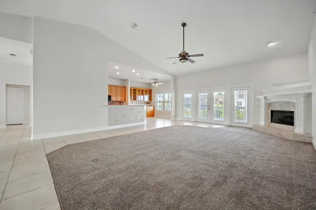 an empty room with chandelier fan and windows