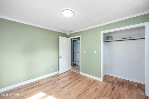 a view of an empty room with closet and a window