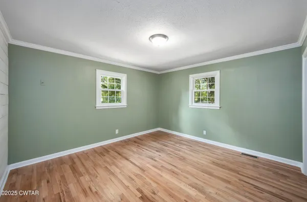 a view of a big room with wooden floor and windows